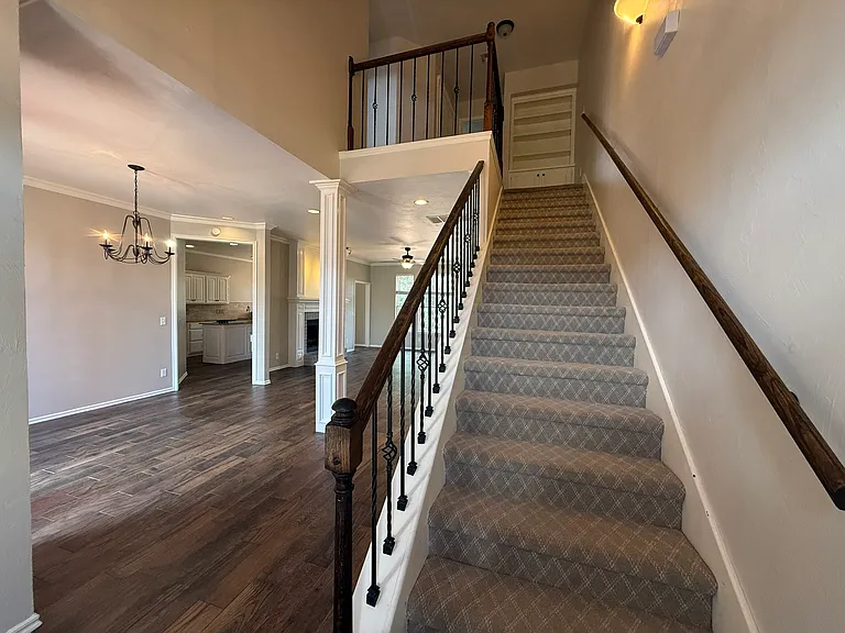 Staircase leading upstairs with storage at the top of the staircase. To the left is the formal dining room with formal living pushed to the back side.