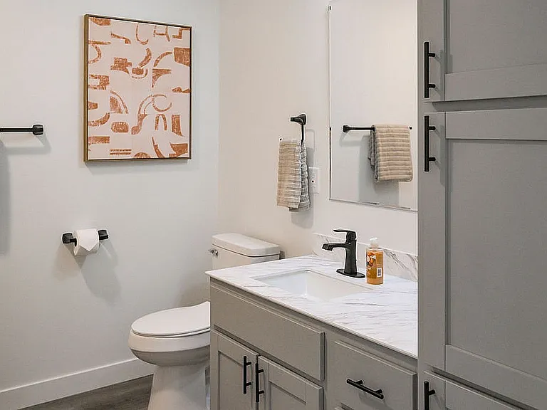 Chic modern bathroom with sleek cabinetry, elegant fixtures, abstract wall art, and inviting neutral tones.