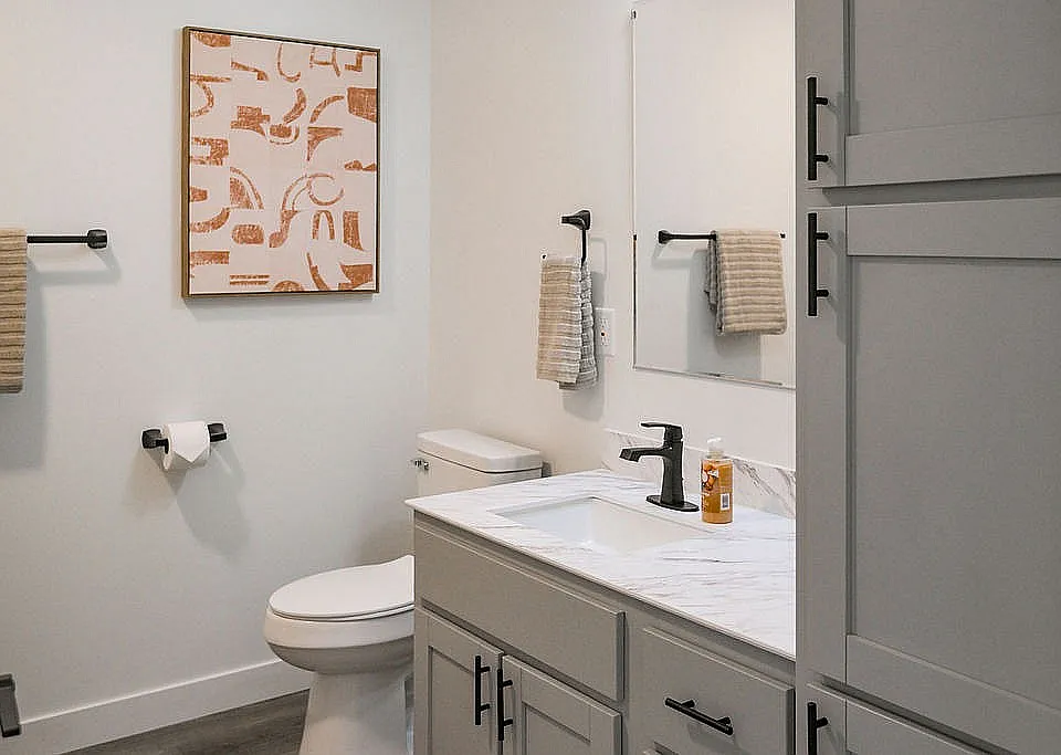 Sleek modern bathroom with elegant fixtures, marble countertop, and abstract wall art, blending style with functionality.