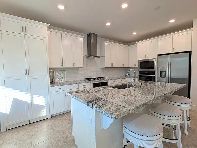 Modern open-concept kitchen featuring premium stainless steel appliances, expansive center island, and sleek cabinetry. The heart of the home, this space flows perfectly into the great room, perfect for entertaining and family gatherings.