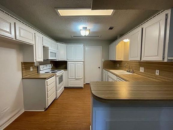 Kitchen with sink, hardwood / wood-style floors, white appliances, and backsplash