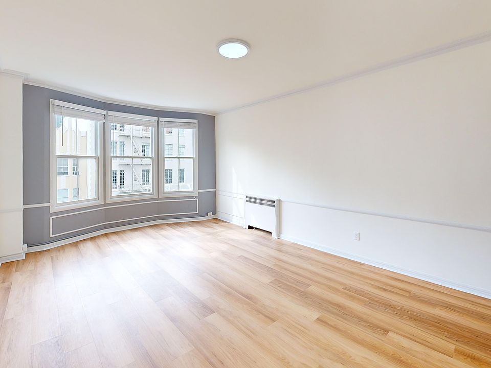 Spacious room with hardwood flooring and a bay window offering natural light from the outside
