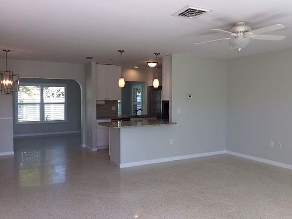 View of living, dining, kitchen and entry to sun room. Terrazzo floors throughout.