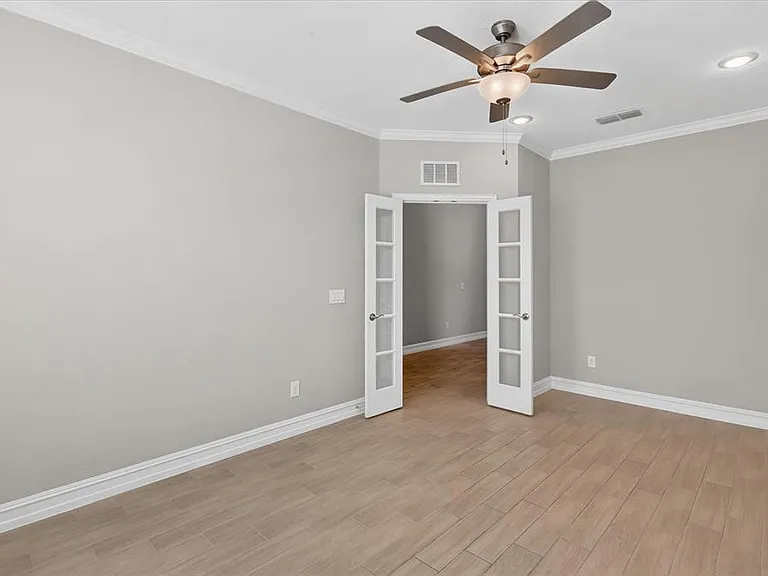 Room featuring light wood-finish flooring, light gray wall paint, and white crown molding