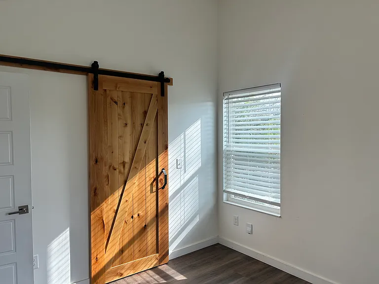 Custom barn door to bathroom provide pleasing aesthetic and space saving.