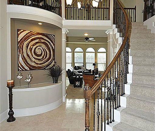 Spectacular entry with  curved wrought iron staircase, gorgeous chandelier, lighted art niche, Juliette balcony, and brick pattern laid tile flooring