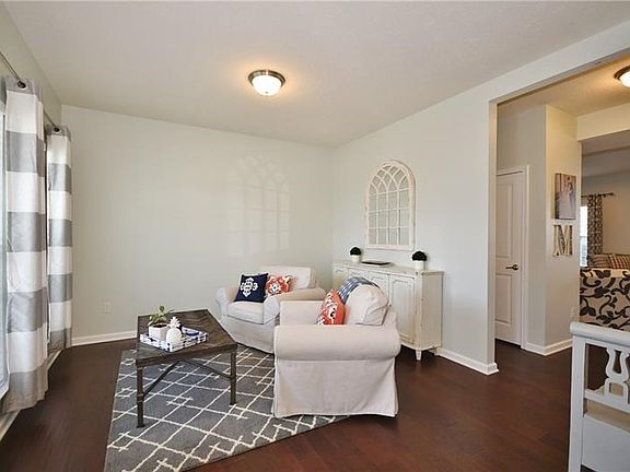 Charming sunlit living room with hardwood floors opens to the family room.
