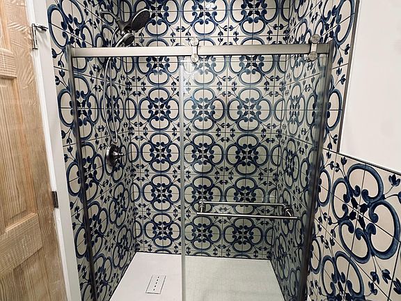 Newly renovated bathroom, walk in shower with rain shower head, handheld shower head, glass sliding door. Water saving toilet, beautiful marble vanity, Spanish wall tile. View of the shower