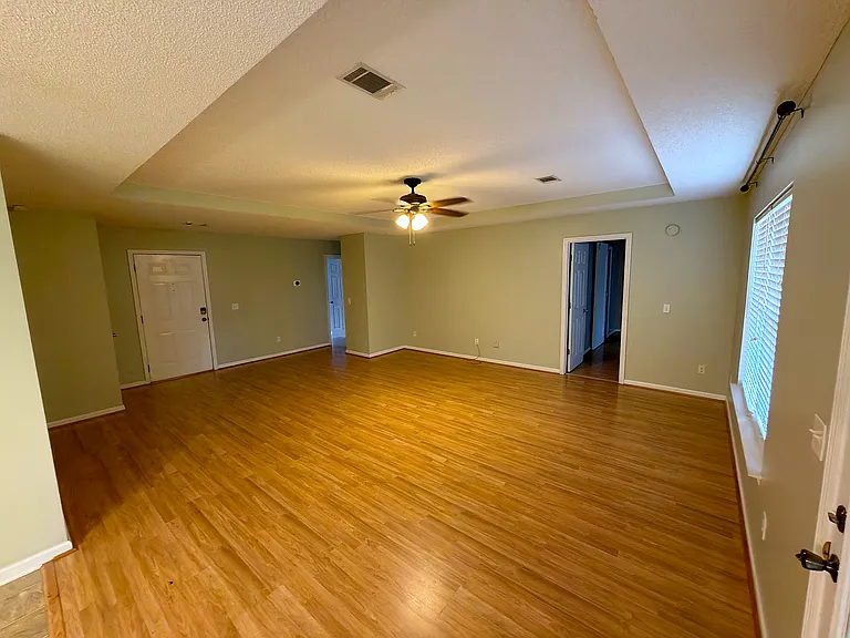 Open living room with durable wood-look flooring and a ceiling fan