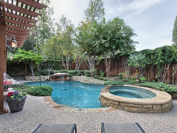 Expansive pool displays a beautiful stone waterfall accented with a flag stone patio area.