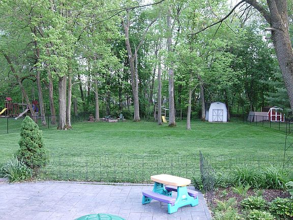 Large fenced yard with a creek just past fence and trees.