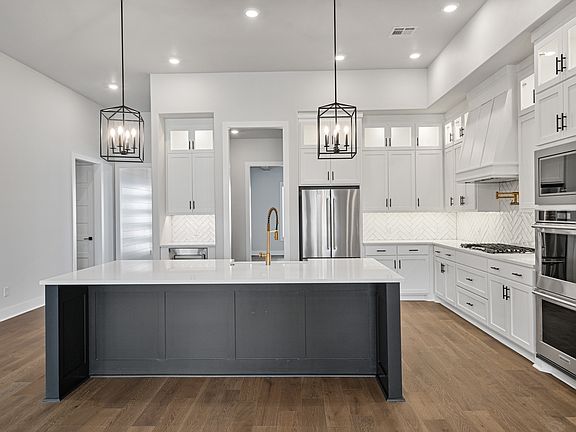 The upgraded kitchen has beautiful white wood cabinetry and tile backsplash.