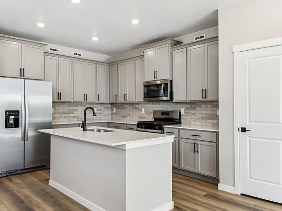 The kitchen has stainless steel appliances and plank flooring.