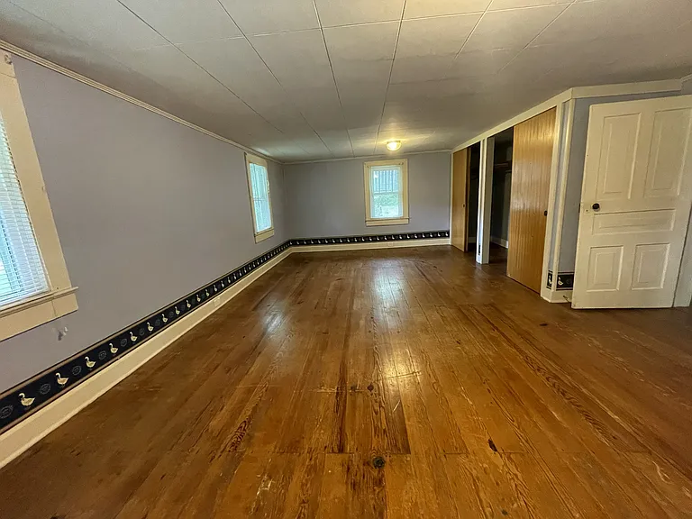 Bedroom #1 spans the front of the home, complete with 2 large closets, windows on 3 sides and original hardwood floors.