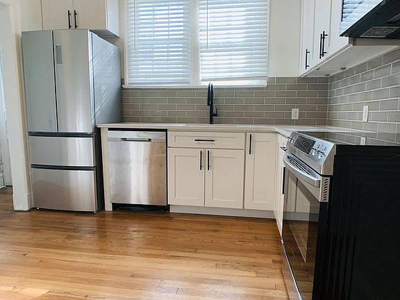 Kitchen has refinished original wood floors and new gray subway tile backsplash