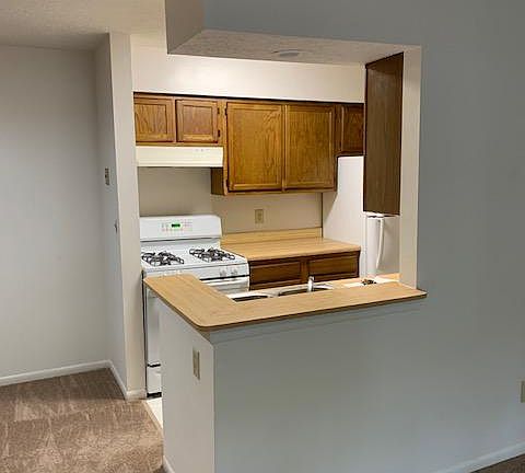 Galley style kitchen with white appliances- gas stove, dishwasher and refrigerator