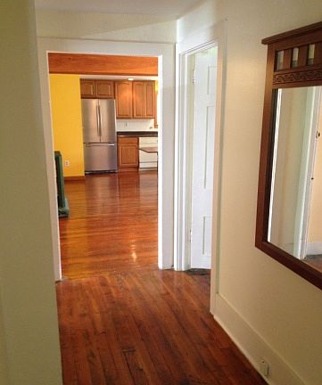 Hallway as seen from the living room with bedroom doors opposite one another (only one door shows in the photo) and leading to the kitchen