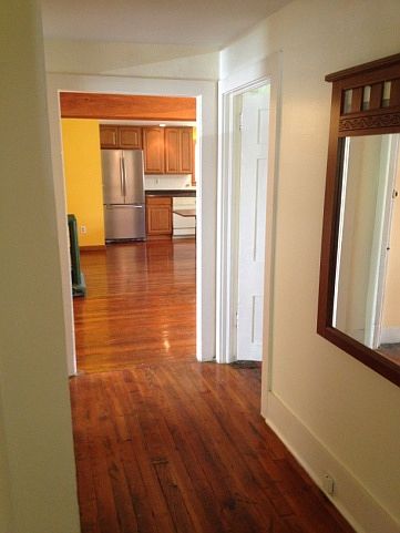 Hallway as seen from the living room with bedroom doors opposite one another (only one door shows in the photo) and leading to the kitchen