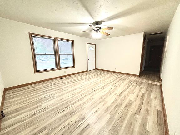 Large living room with new flooring and window treatments.