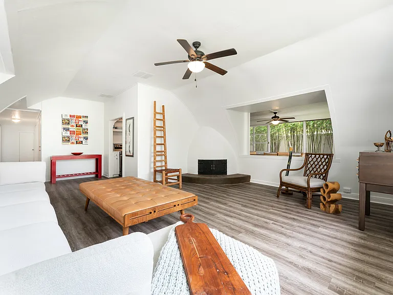 Additional view of the main living area with vaulted ceilings and decorative non-functioning fireplace.