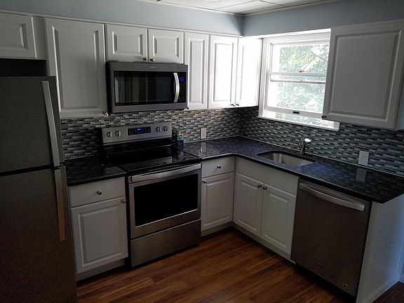 Window view of tree tops, and showing dishwasher.