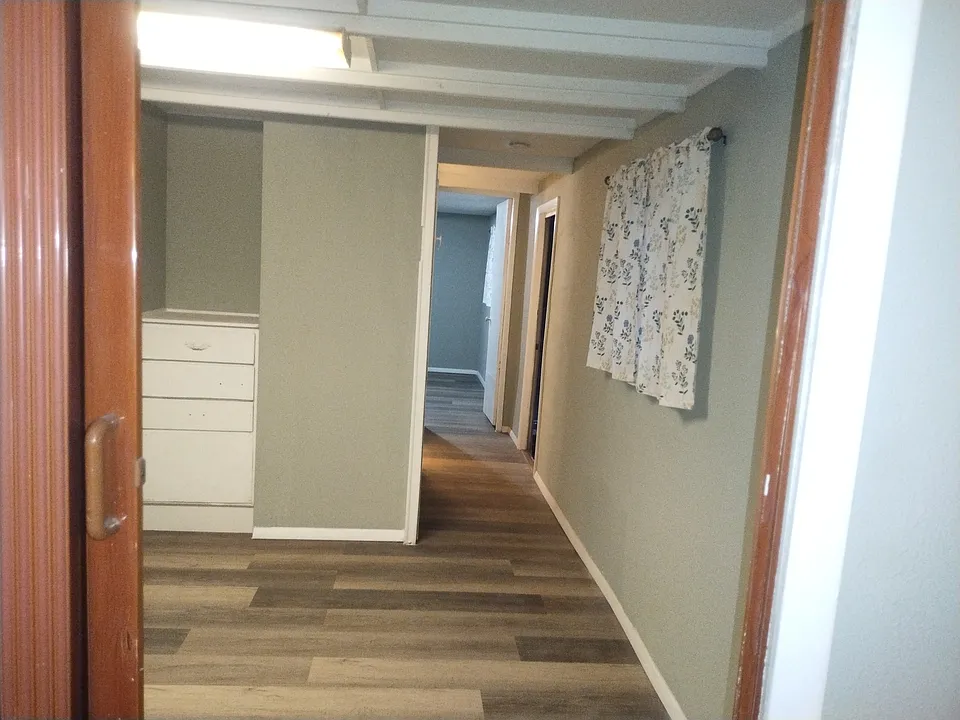 2nd upstairs bedroom with new laminate floor, built in drawers for clothes or other items, window with curtains, privacy red door and passageway to the bathroom and master bedroom