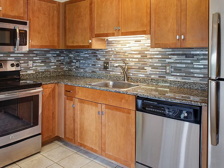 Modern kitchen features stainless steel appliances, granite countertops in select homes