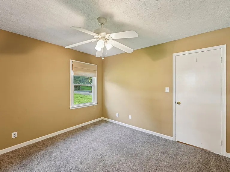 A peaceful bedroom with soft carpet, warm golden walls, and gentle natural light, creating a cozy little haven for rest, comfort, and quiet retreat.