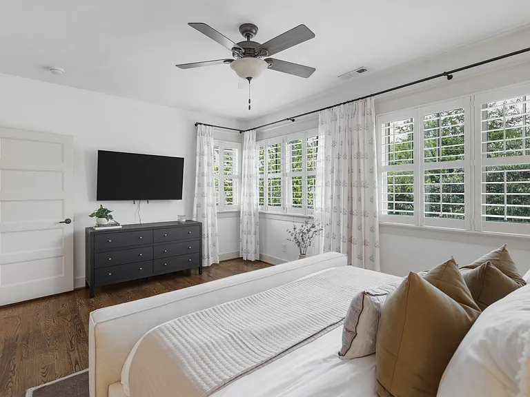 The primary suite features a king-sized bed, huge walk-in closet, ceiling fan, dresser, smart TV, and ensuite bathroom.