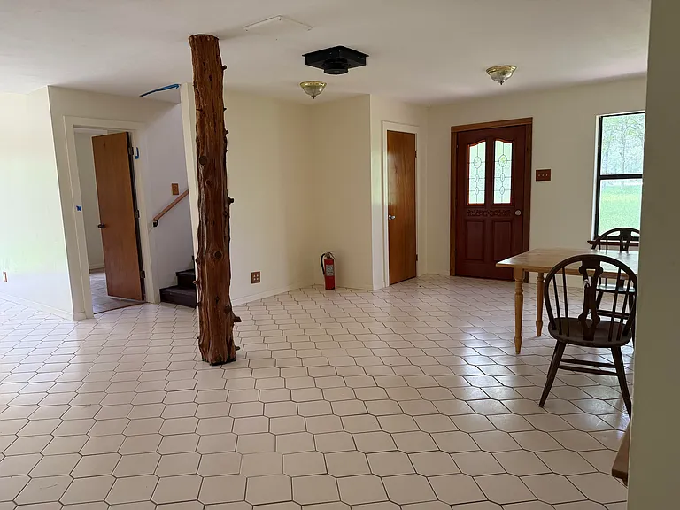 Living room showing a bedroom entrance, under-stairs closet, and the front door,