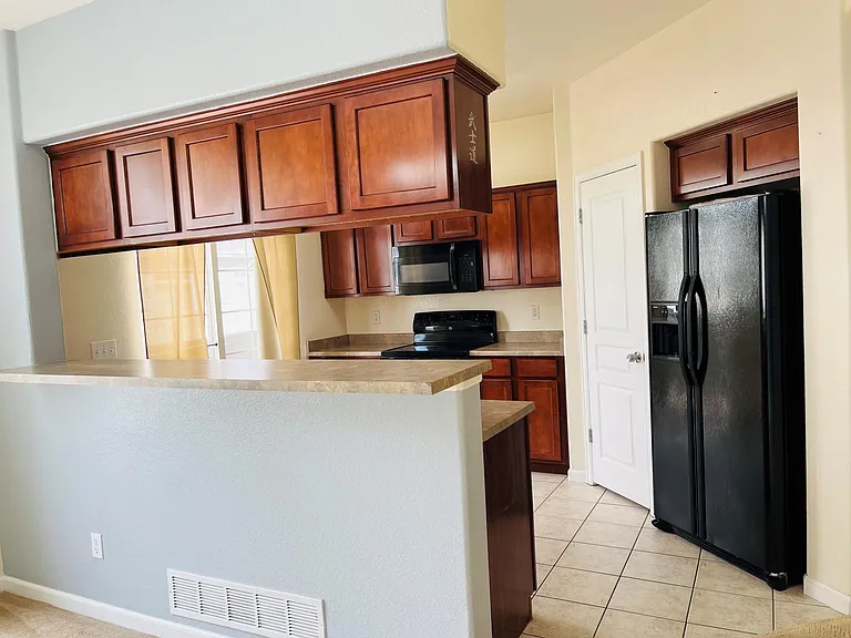 Kitchen is equipped with an ice and water filtration system refrigerator, dishwasher, stove with an overhead microwave, beautiful cherry finish cabinets, and a small balcony.