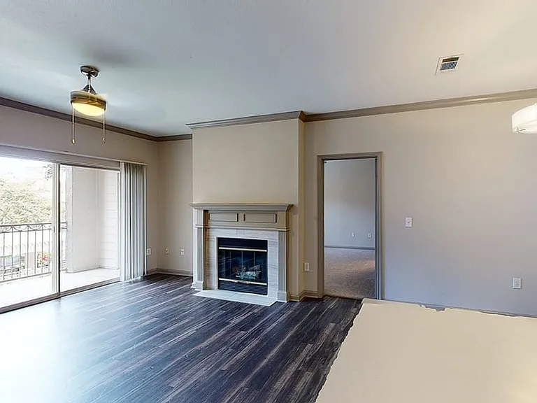 Apartment living room with wood-style flooring and fireplace in select homes.