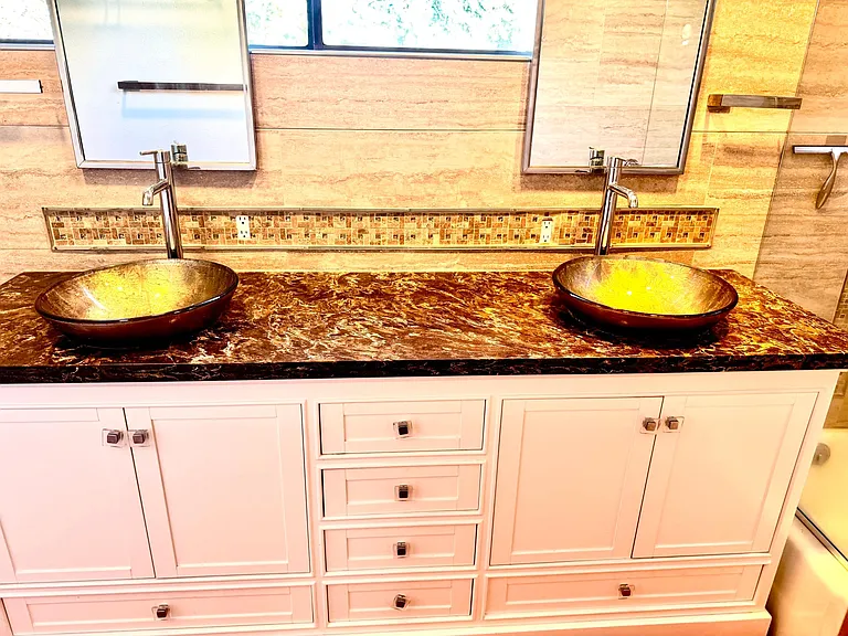 Double sinks with views of the forest. All design marble and tile insert build, with granite counters, Delta faucets, custom sink basins, hardwood his/her spacious cabinets and drawers.