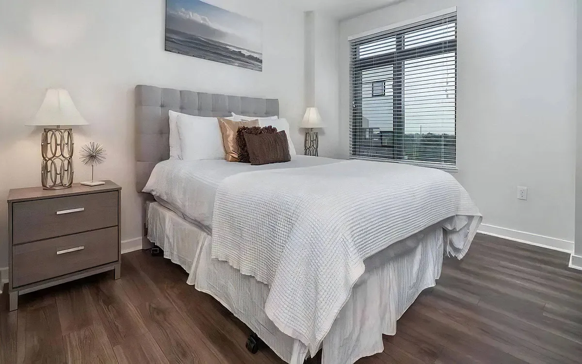 Apartment Bedroom Featuring Full-Size Bed and Hardwood Flooring - The Barton at Woodley