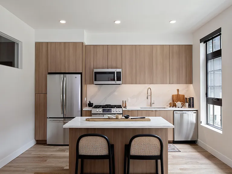 Light wood, frameless cabinetry with white quartz countertops