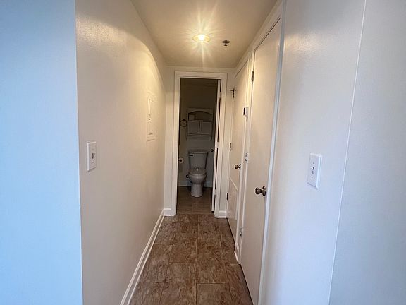 Hallway with pantry on right and bathroom entry at end.