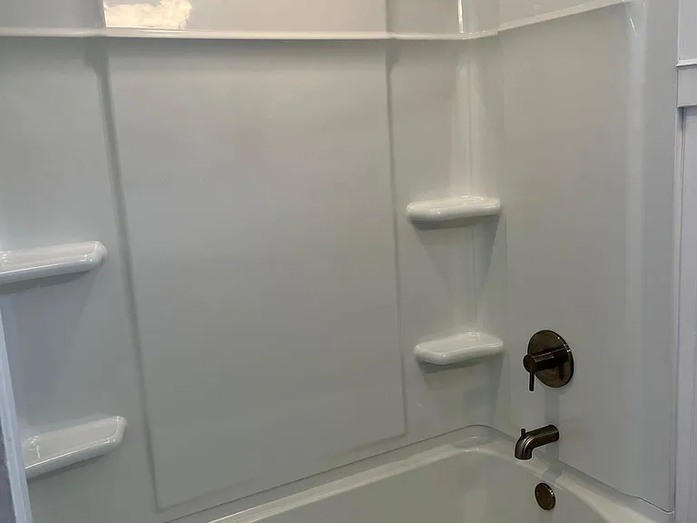 New tub and shower surround with brushed nickel fixtures.