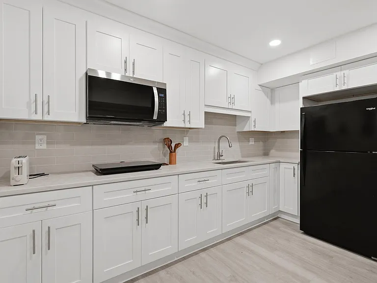 Updated kitchen with shaker cabinets, ample counter space, tile backsplash, and stainless microwave plus full-size fridge.