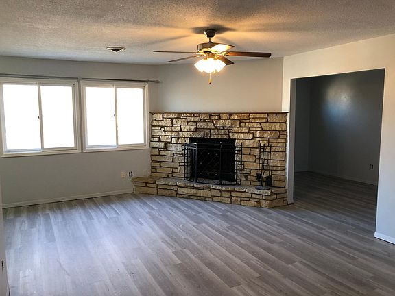 Living room with Fireplace, ceiling fan, and wood floors. Den to the right.