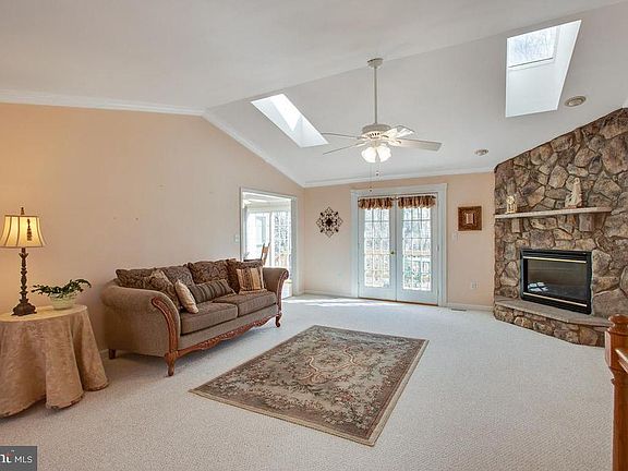 Living room features stone fireplace and skylights