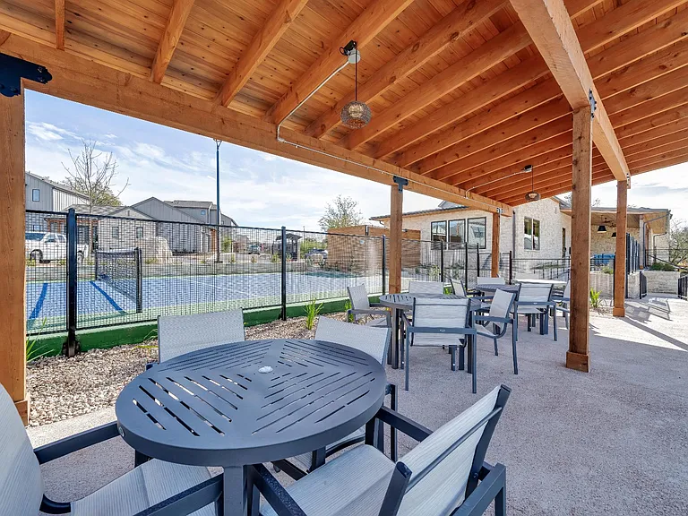 A wooden pergola over a table and chairs.