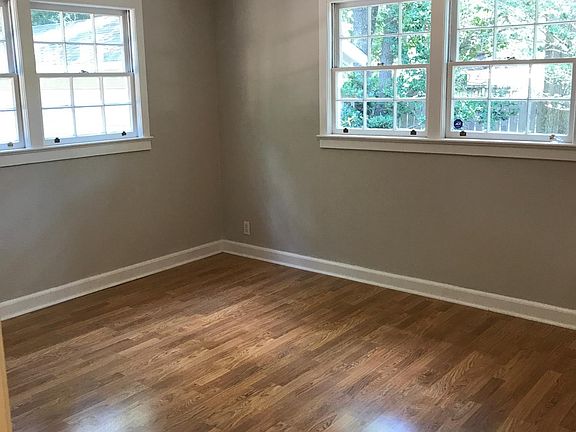 Large bedroomin the rear of the house with newly finished hardwood floors and bright happy windows