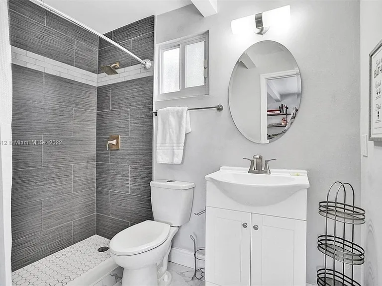 Updated bathroom with a tiled walk-in shower, vanity storage, and a window for ventilation and natural light.