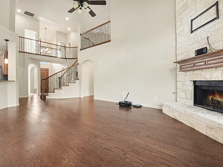 Expansive living area featuring wood-finish flooring and a stone fireplace with a substantial wooden mantel