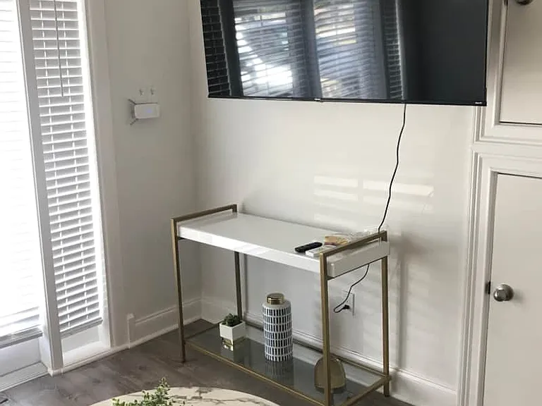 Bright studio with beautiful blinds, window, Smart TV, and decorative coffee table.