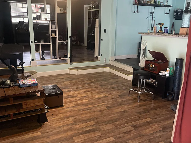Multi-level common area with durable wood-look flooring, open shelving, and space for seating, work, or storage.