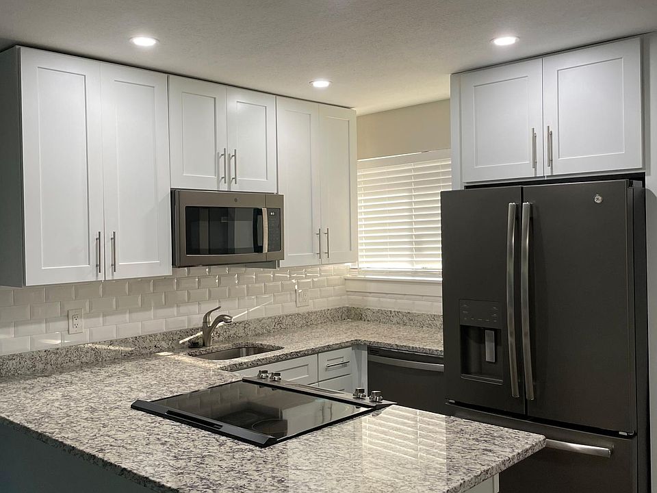 Open concept Kitchen with large granite island, stainless steel appliances. Oversized white shaker cabinets to ceiling, and recessed lighting.
