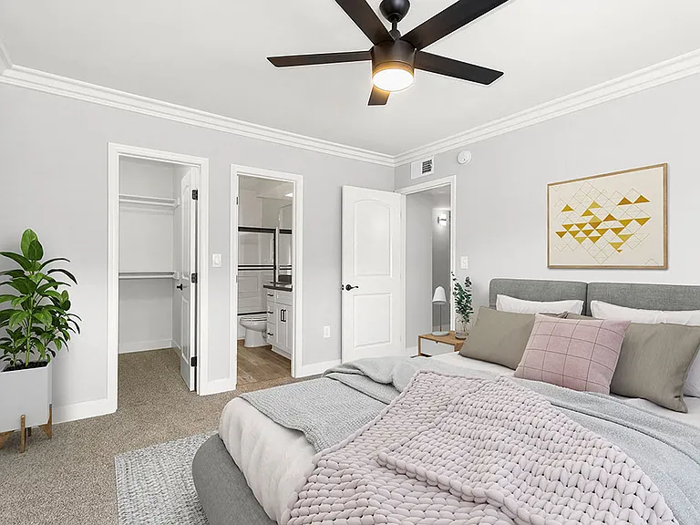 Carpeted bedroom with ceiling fan and private bathroom.