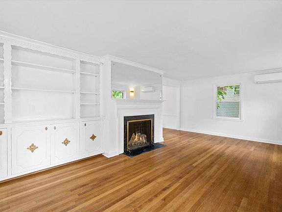 An alternative view of the living room showcases the built-in shelves, closed storage, and fireplace.