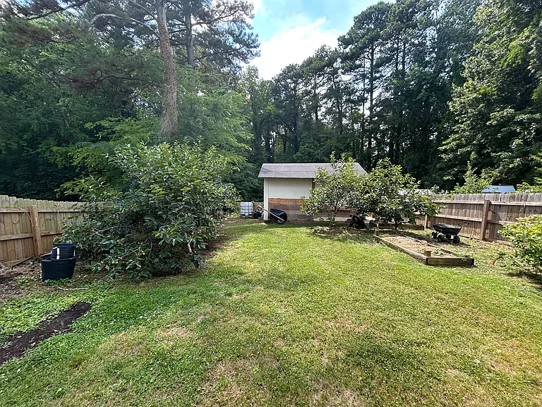 Standing from the house, this is the view of the first half of the backyard/garden. The custom-built wooden shed in the middle of the backyard is sturdy, well-built, and perfect for storing garden tools, supplies, or anything else you need tucked away.